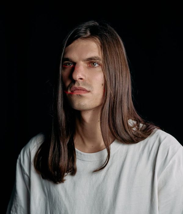 Man in a focused, calm gymnastic pose against a dark background.